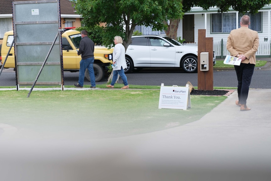 Nathan stands on a driveway as people who viewed the hosue walk by on the footpath.