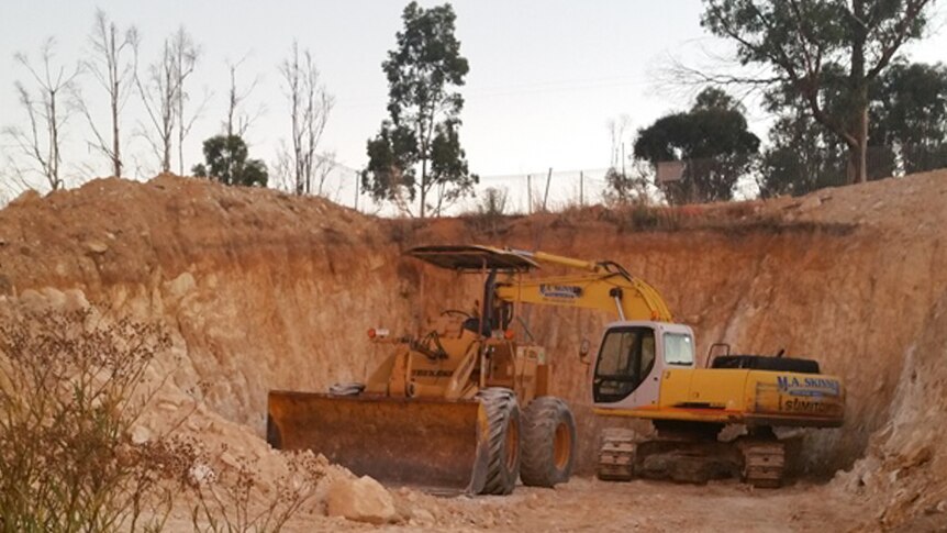 A digger and front-end loader in the huge hole that will house their home.
