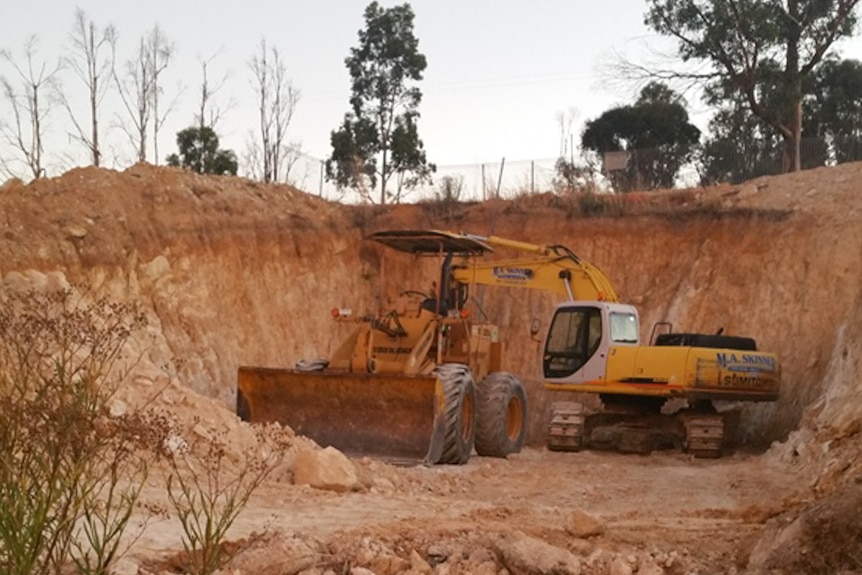 A digger and front-end loader in the huge hole that will house their home.