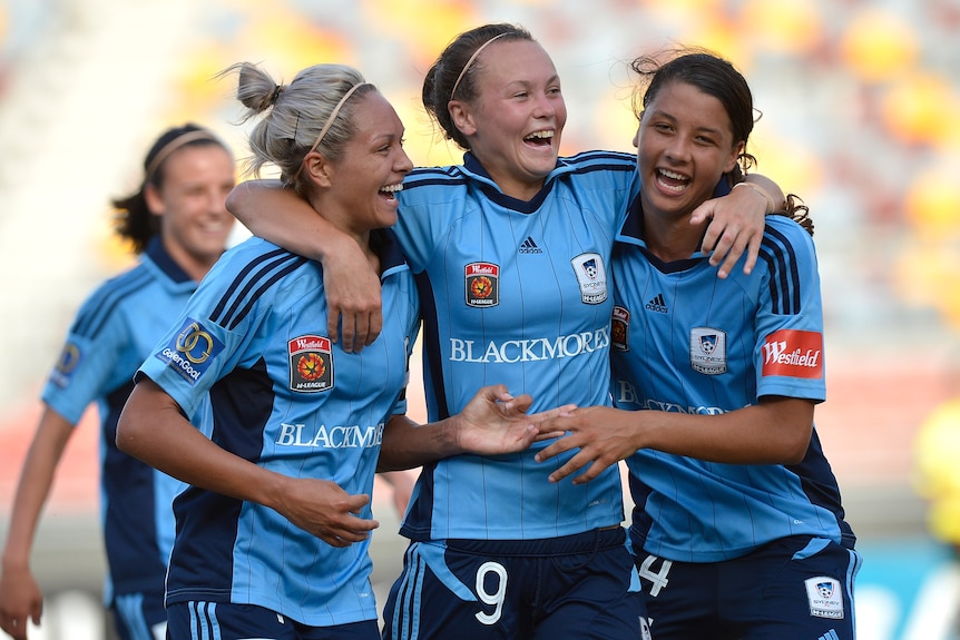 Soccer players wearing sky blue smile with their arms around each other