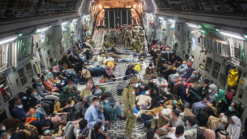 Citizens and soldiers crowd the inside of a military aircraft.