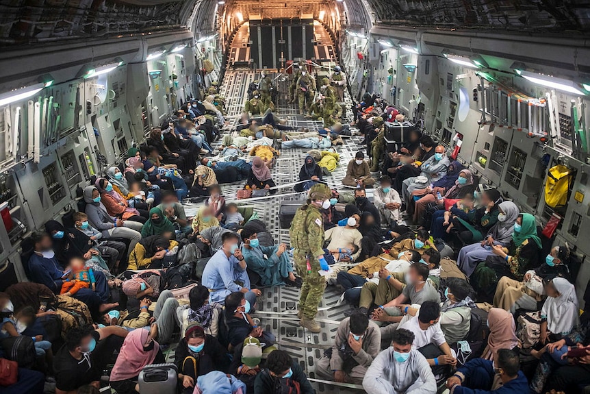 Citizens and soldiers crowd the inside of a military aircraft.