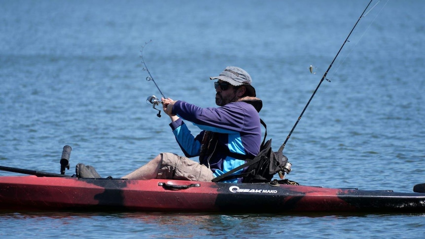 A paddler casts a line out to catch a fish.