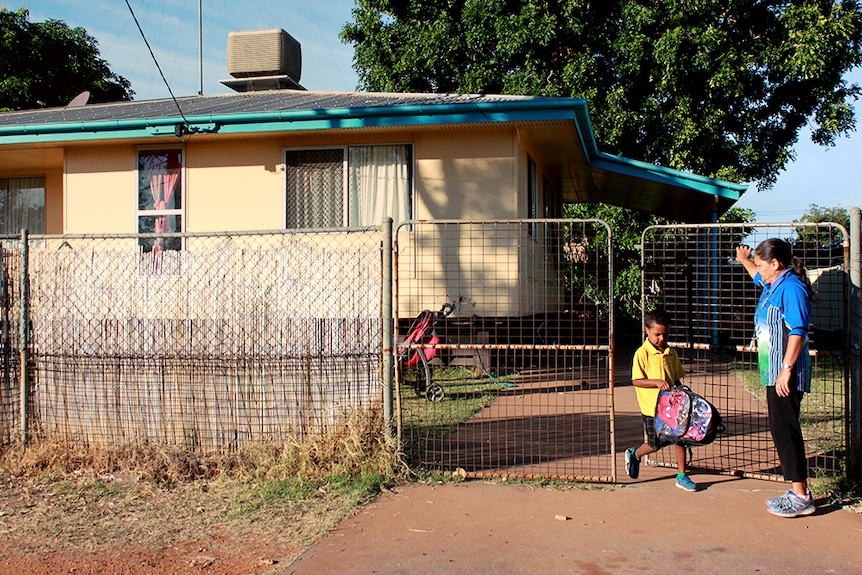 Indigenous Education Worker Jenny Craigie helps a young student out the gate and onto the school bus.