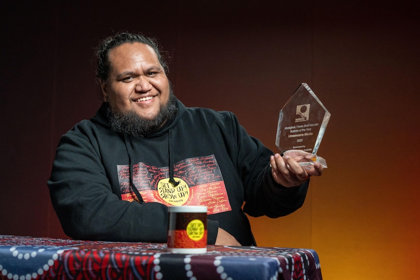 Dre Ngatokorua holding up the NAIDOC business of the year award on the set of NAIDOC News.