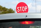 A handheld stop/slow sign at roadworks.