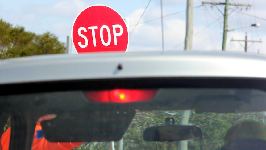 A handheld stop/slow sign at roadworks.