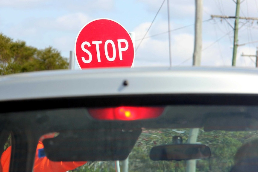 A handheld stop/slow sign at roadworks.