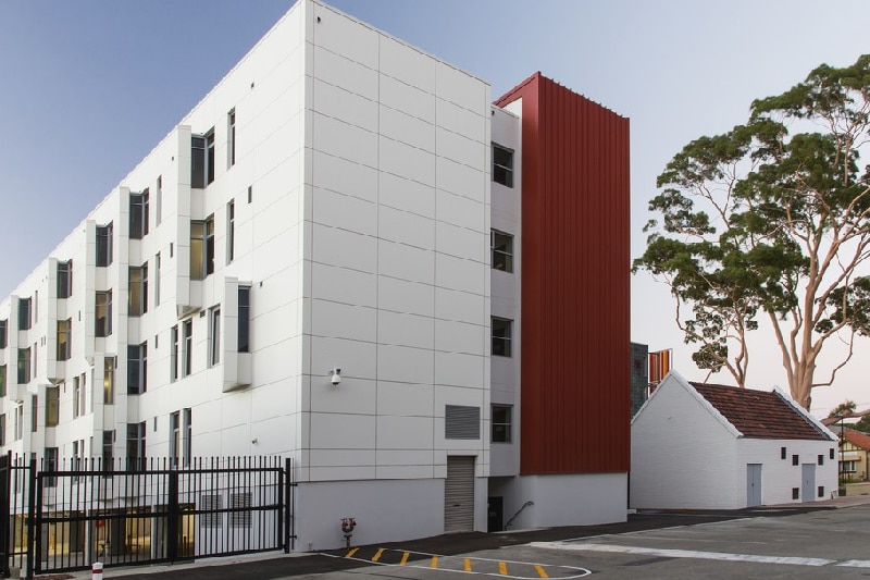 A wide shot of a four storey residential building clad in white panels.