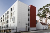 A wide shot of a four storey residential building clad in white panels.