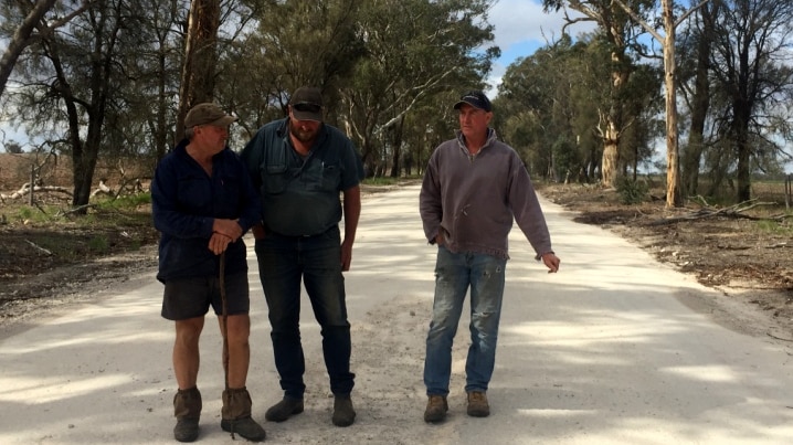 Three men on dusty regional road.