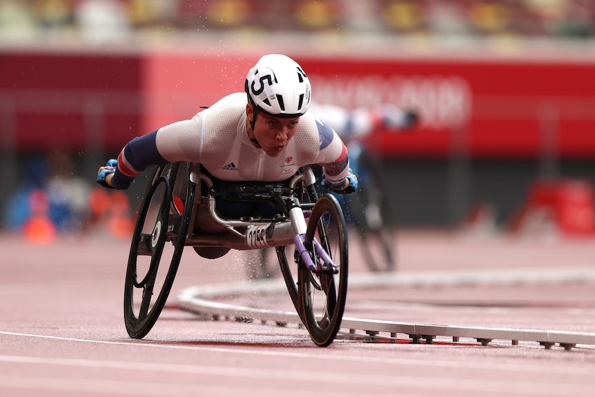 A wheelchair racer on the track, pushing her chair in a race
