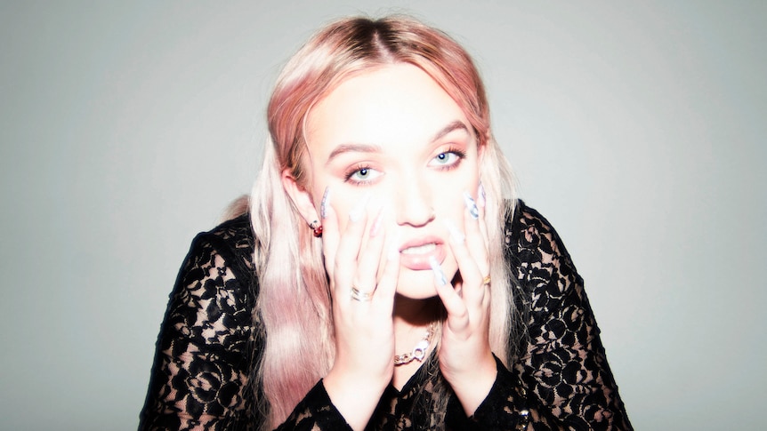 Overexposed photo of George Alice in a black lace top with pink hair as he holds her face in her hands.