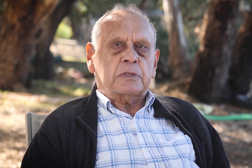 an older man is standing among trees staring at the camera