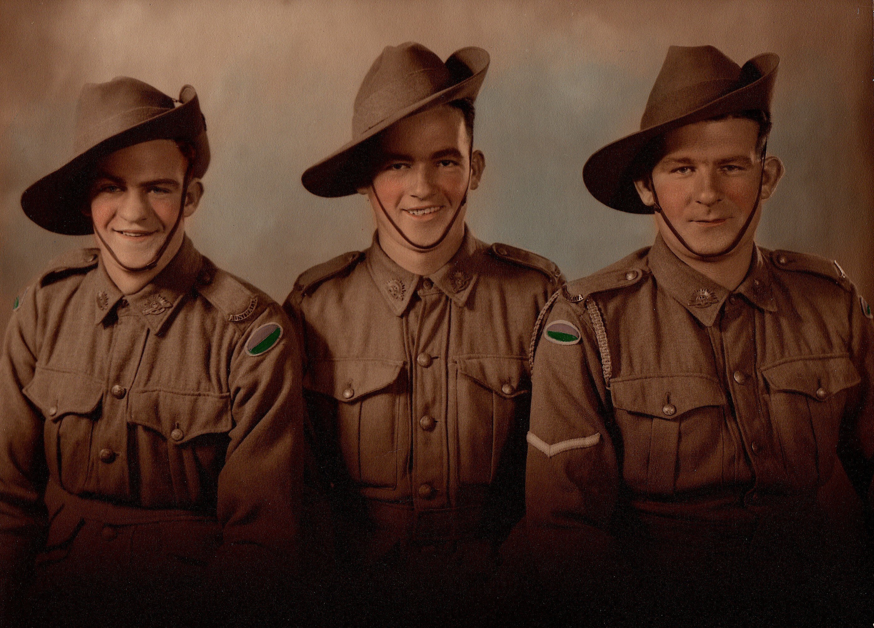 The Australian soldiers in a coloured photograph sit in a row. 