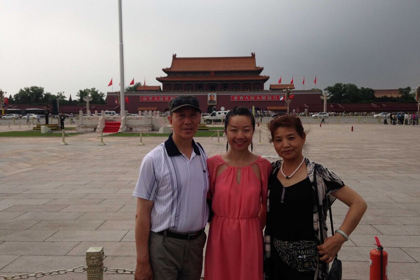 A young women poses with her parents at tiananmen square