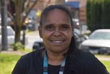 A young Indigenous woman with long brown hair smiles at the camera.