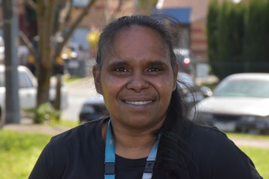 A young Indigenous woman with long brown hair smiles at the camera.