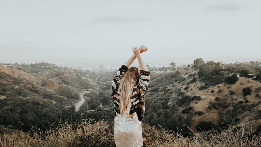 A woman stands with her arms raised.