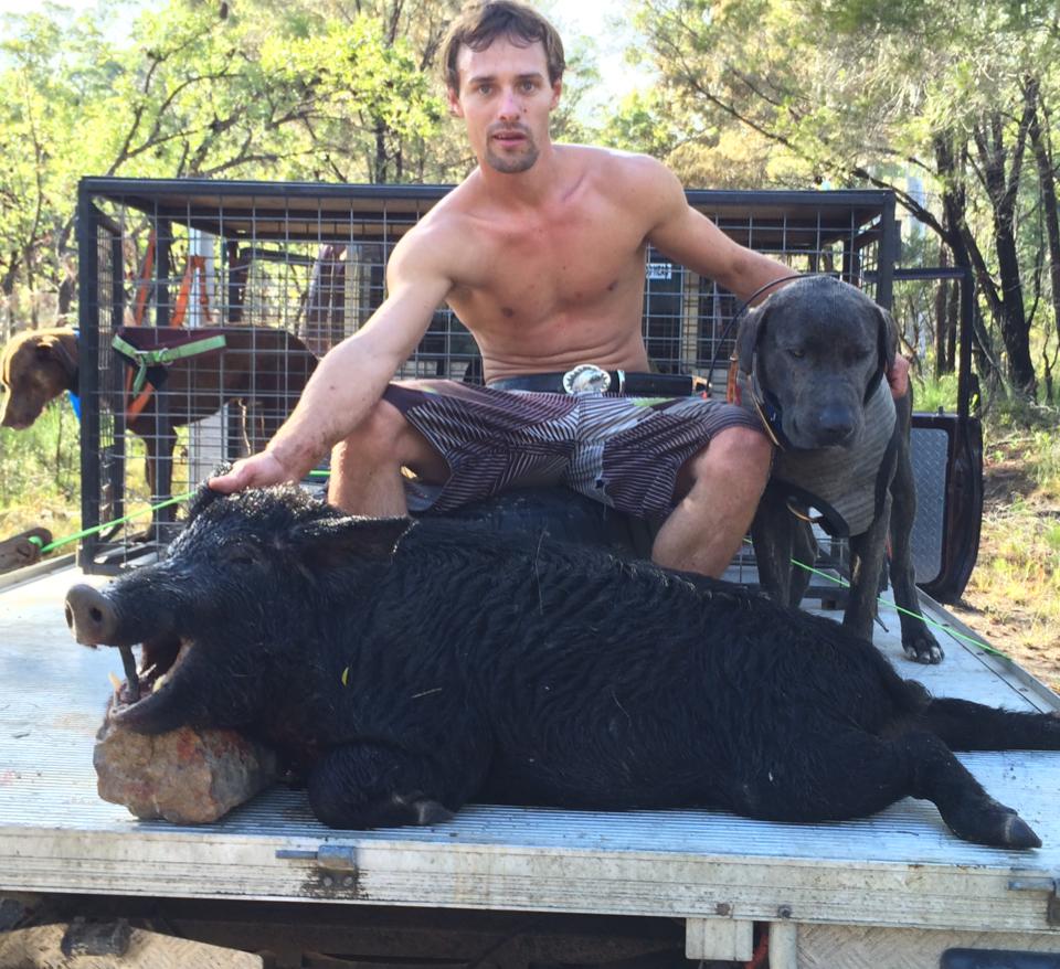 A man sits with a dead pig