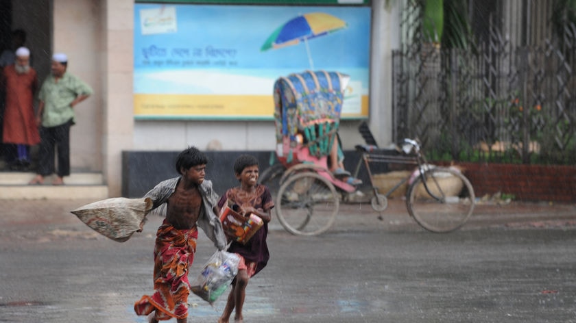 Two Bangladeshi children run for shelter from the rain in Dhaka.