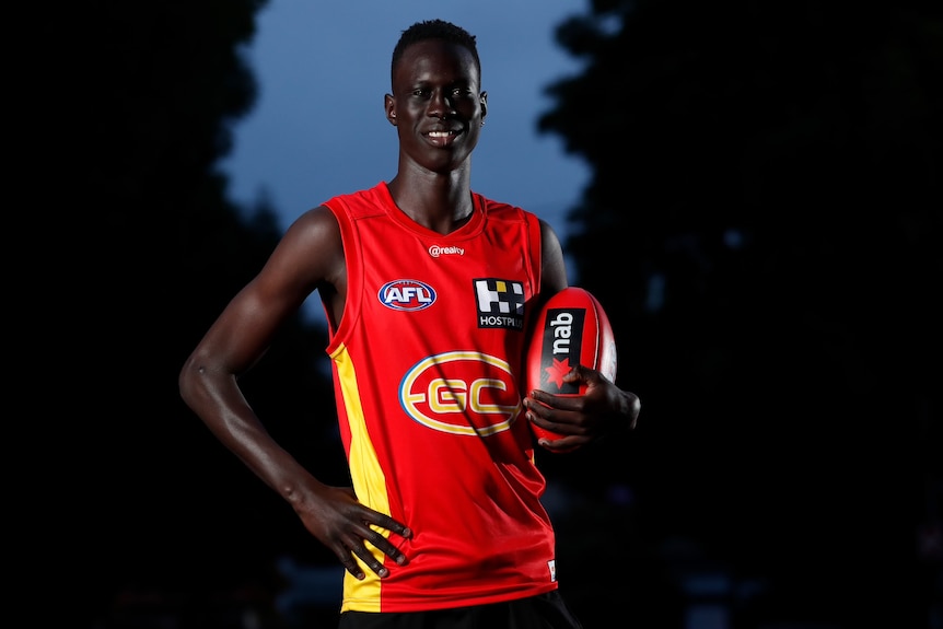 Mac Andrew dressed in footy jumping and holding a ball.