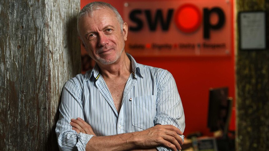 A man standing against a red background.