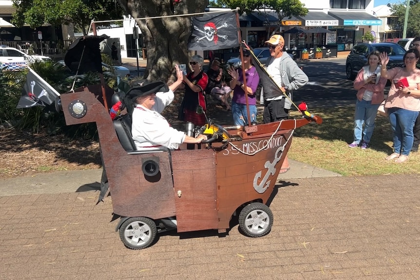 A lady on a scooter that is decorated to look like a ship
