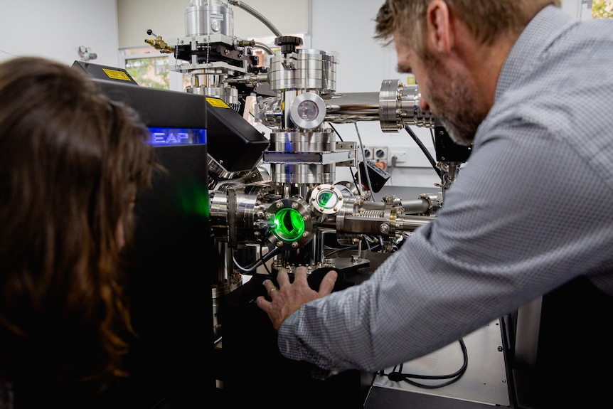 two scientists in a lab with a green atom probe