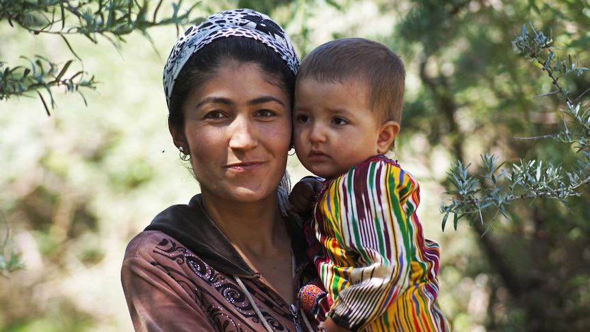A mother holding her child in traditional garb