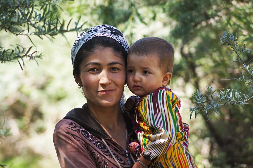 A mother holding her child in traditional garb