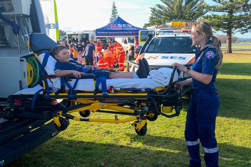 A child being loaded onto a stretcher in a training scenario.