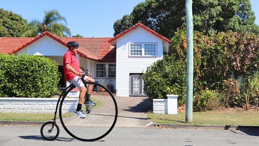Man riding a penny farthing on a local street