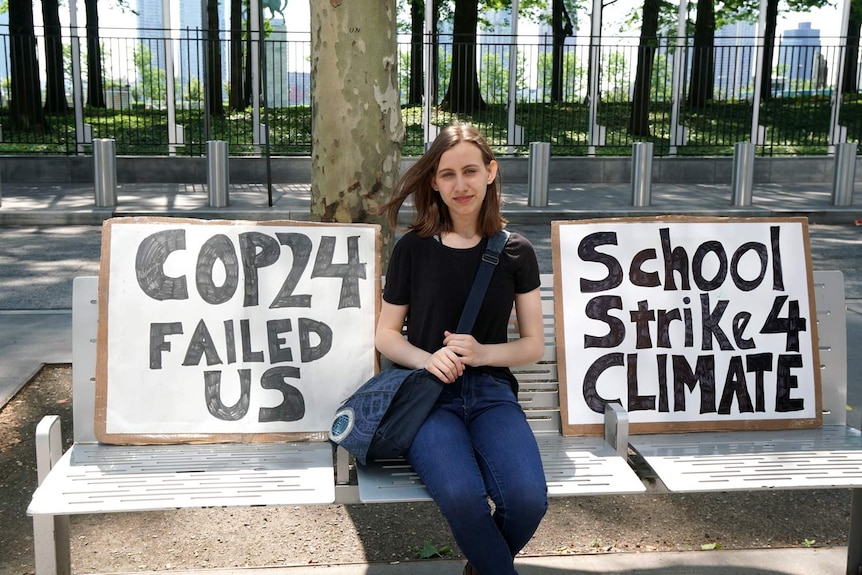 Alexandria Villaseñor sits on a chair. Beside her are placards saying "COP24 failed us" and "school strike 4 climate".