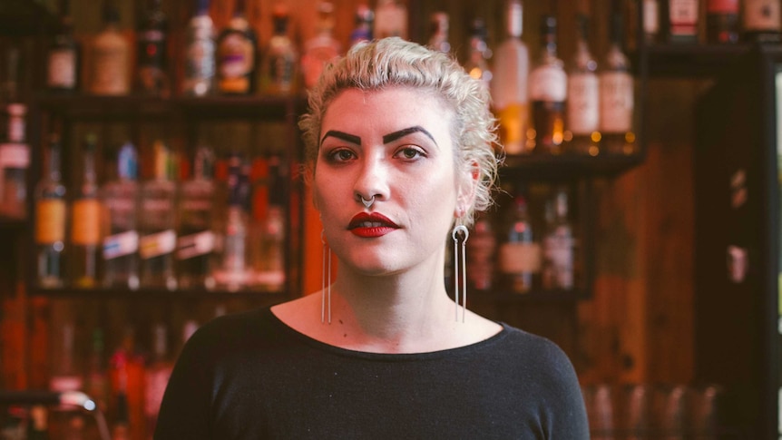 A woman stands behind a bar.