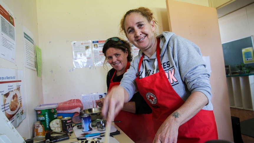 Two women are busy cooking a curry.