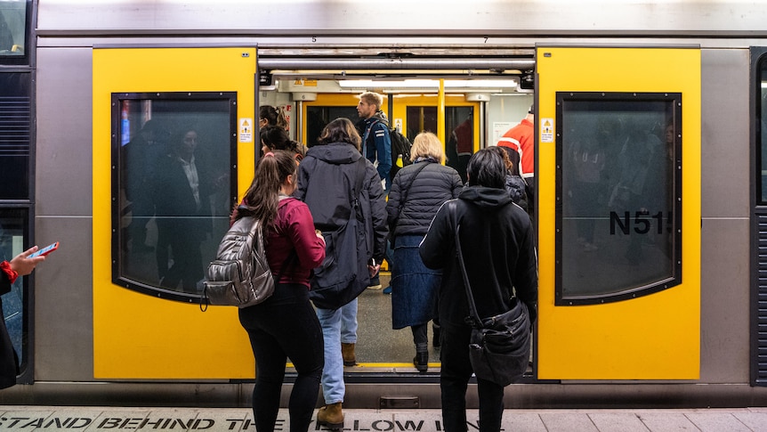 commuters getting on a train at a rail station