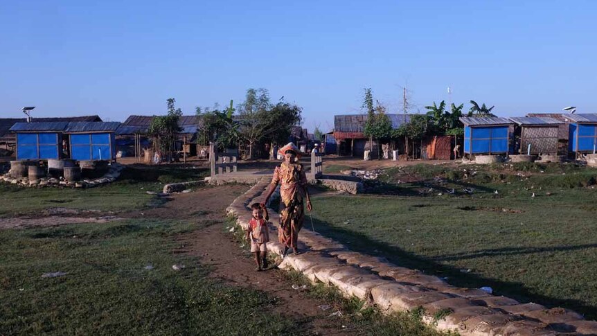 A woman and child walk between two of the better-served camps on the outskirts of the state capital of Sittwe.