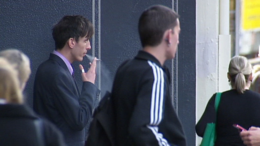 A man smokes on a crowded street