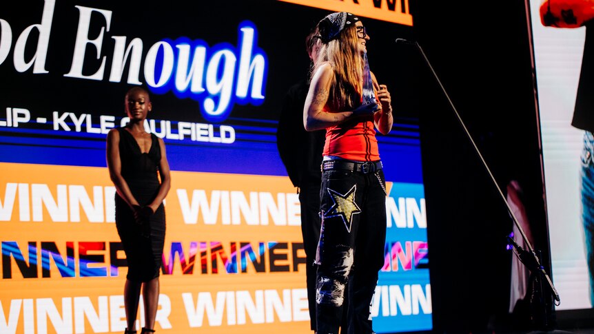 A lady standing on a stage in front of a microphone accepting an award