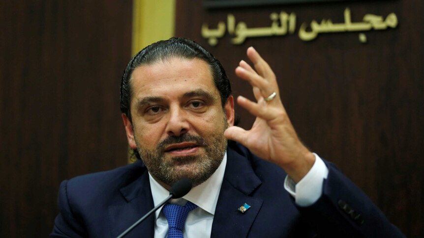 Lebanon's prime minister Saad al-Hariri raises one hand as he speaks into a microphone.