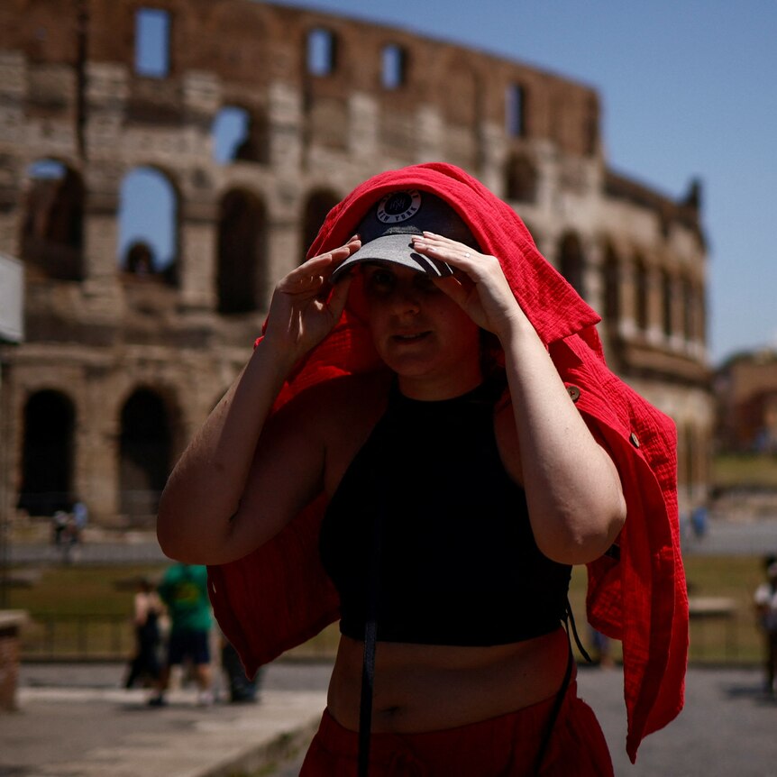 A woman shelters from the sun with a shirt near the Colosseum during a heatwave.