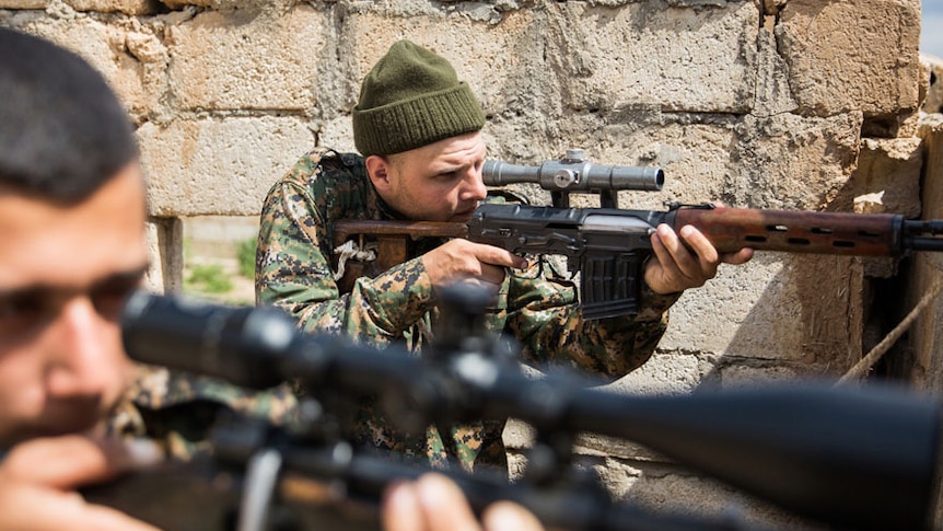 A 26-year old foreign fighter from the US points a gun during a clash with ISIS.