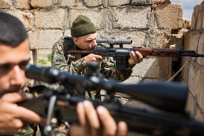 A 26-year old foreign fighter from the US points a gun during a clash with ISIS.
