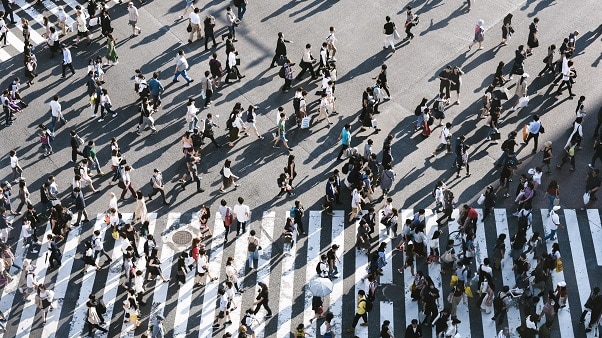 Hundreds of people crossing pedestrian crossings at once in a busy city centre