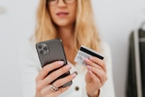 Woman holding a phone and a credit card