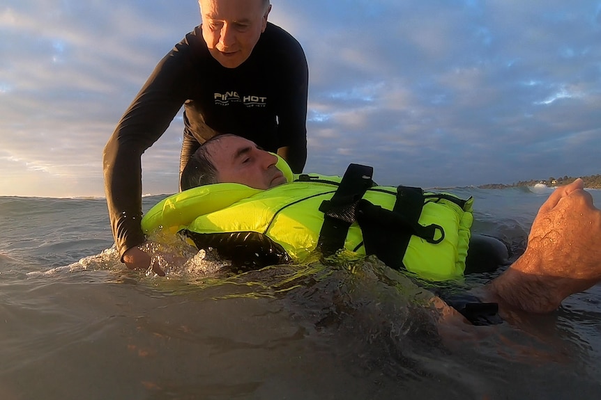 Bob Beekhof floats Pevitt in the ocean