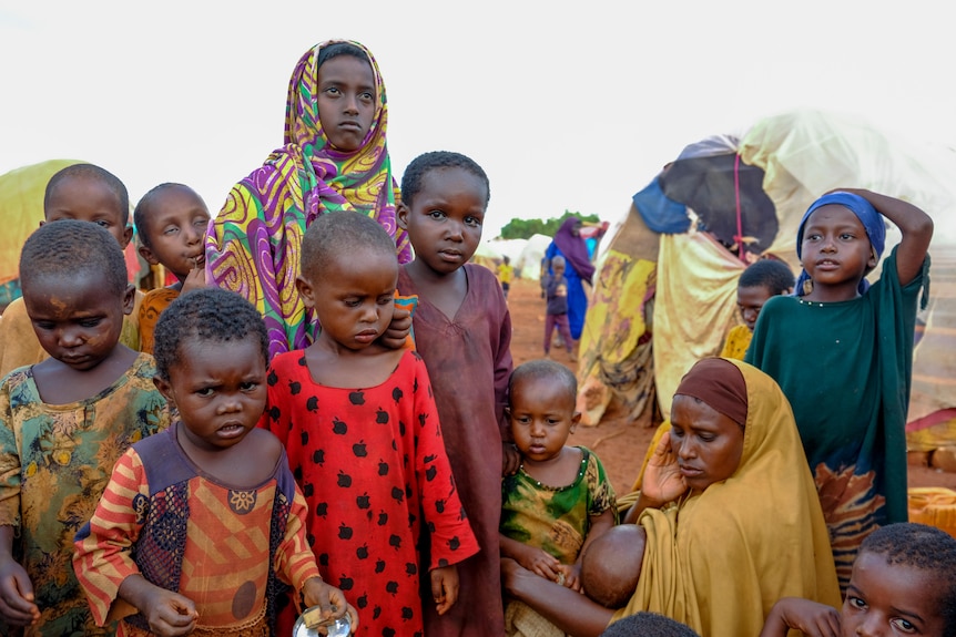 A mother and children displaced by drought sit outside their makeshift shelter in Somalia.