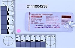 A packet of tablets labelled ivermectin tablets USP against a horizontal and vertical ruler