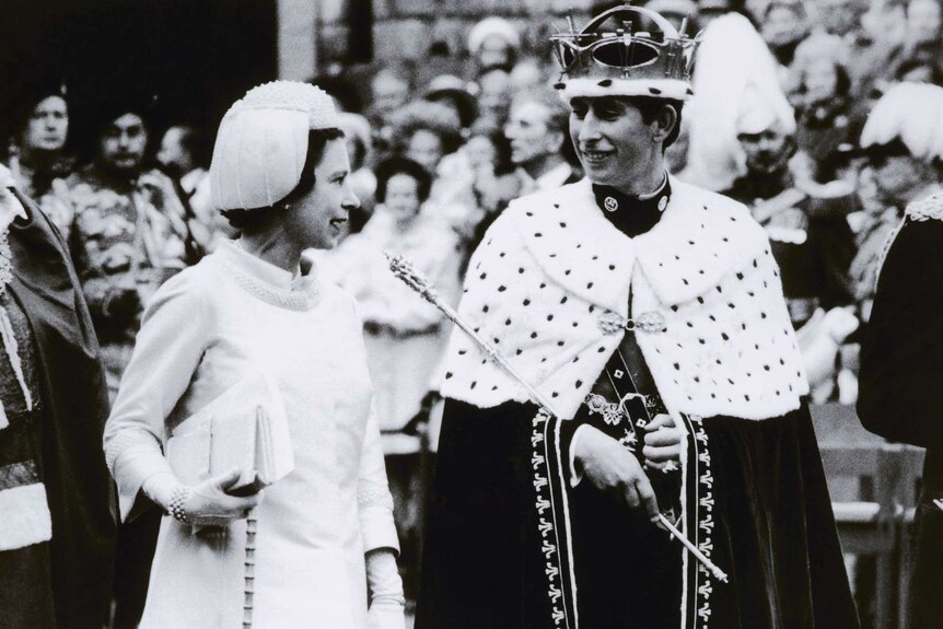 The Queen and the Prince of Wales walk alongside each other.
